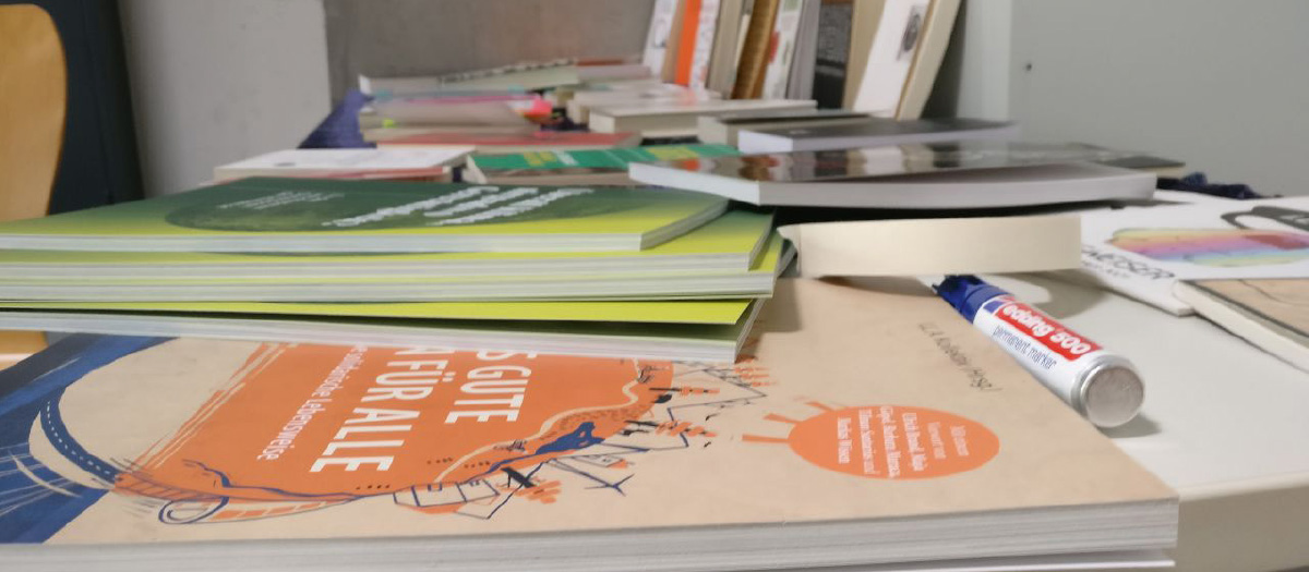 Ein Schreibtisch mit viel Informationsmaterial in Form von Broschüren sowie ein Permanentmarker in blau.